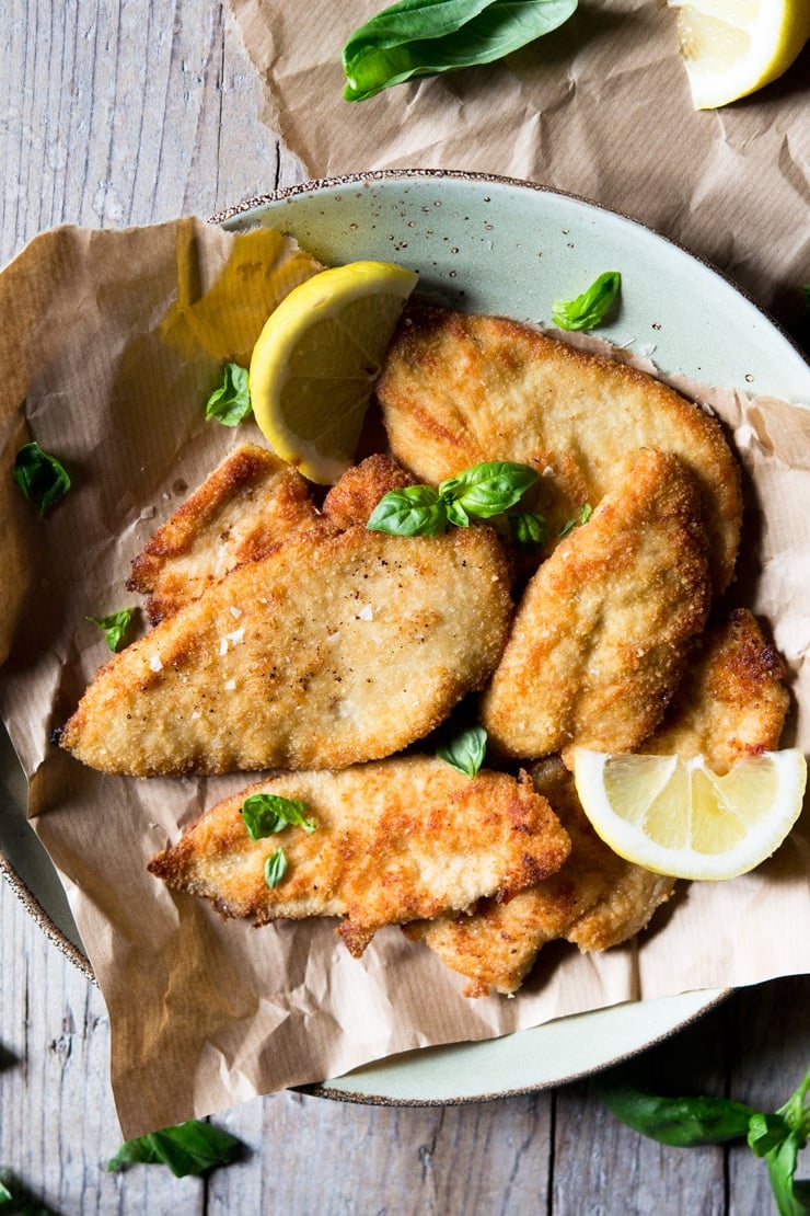 An overhead shot of breaded chicken cutlets on brown paper