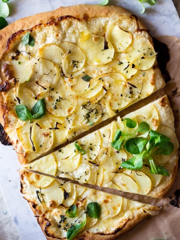 An overhead shot of a potato pizza with a cheesy base