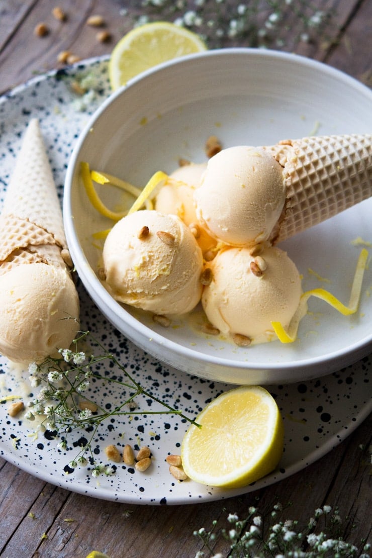 A side shot of sccops of ice cream in a bowl with a cone