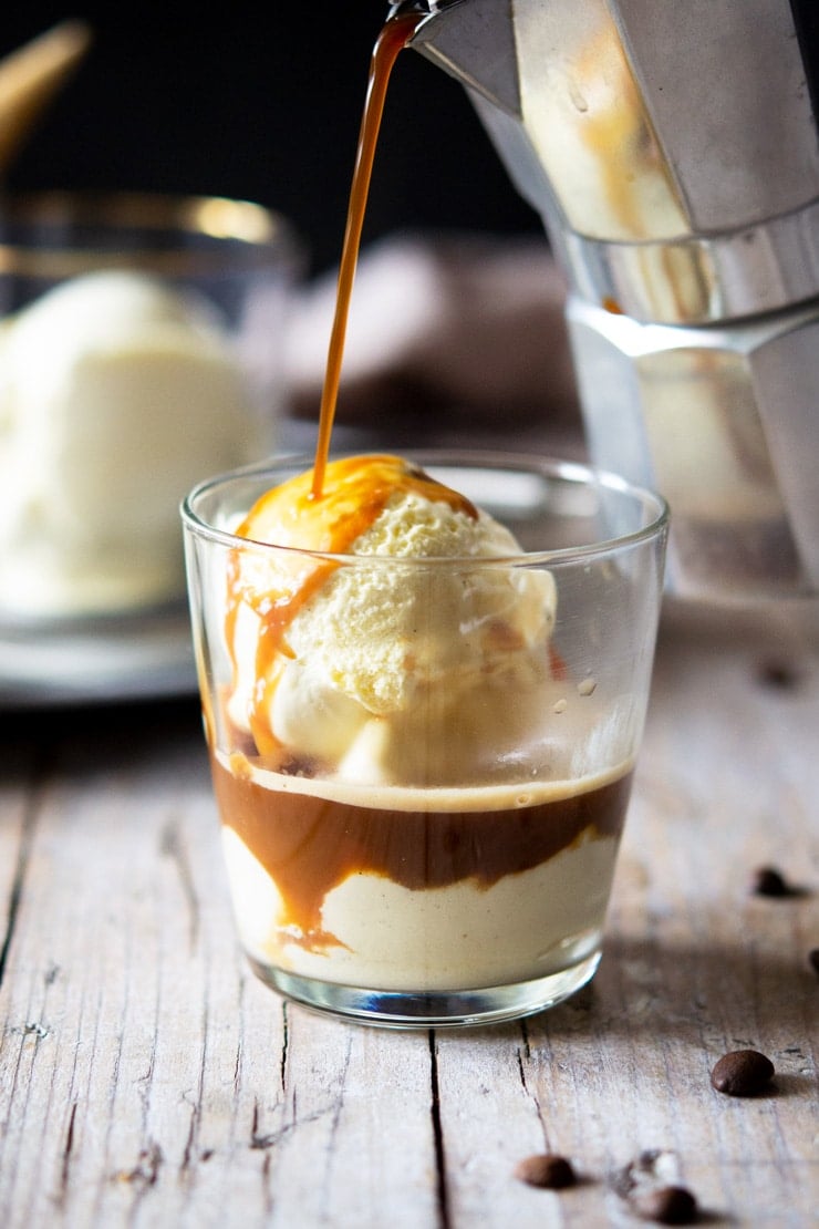 A photo of coffee getting poured over ice cream in a glass to make an affogato