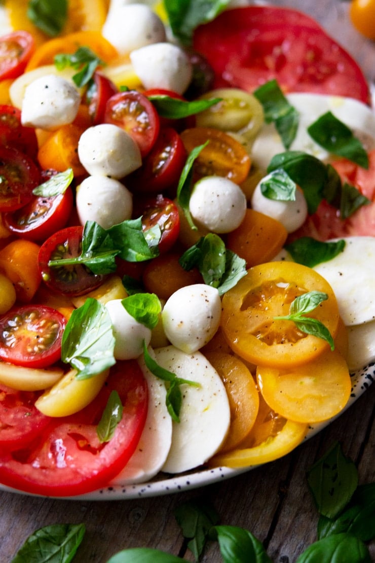 A close up of a a classic caprese salad with different coloured tomatoes