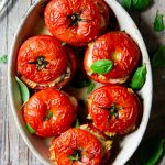 A pin image of baked stuffed tomatoes in a baking dish