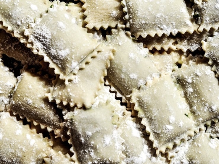 A close up of ravioli cut out perfectly with a ravioli stamp, one of the essential kitchen tools for Italian cooking