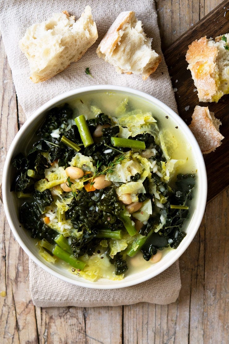 AN overhead shot of Tuscan minestrone soup on a wooden surface