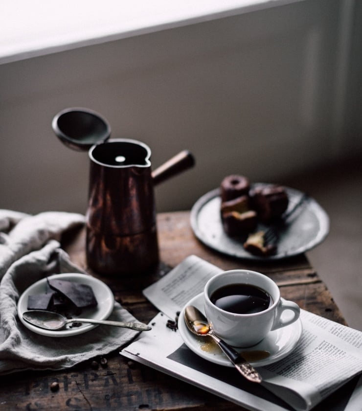 A moka pot and cup of espresso on a wooden table one of the essential kitchen tools for Italian cooking