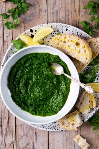 Parsley pesto in a white bowl with a spoon