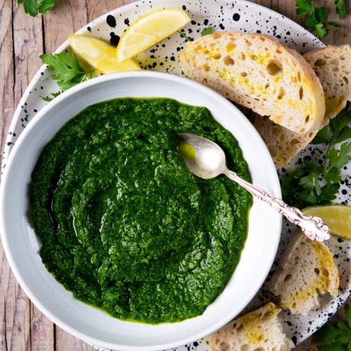 Parsley pesto in a white bowl with a spoon