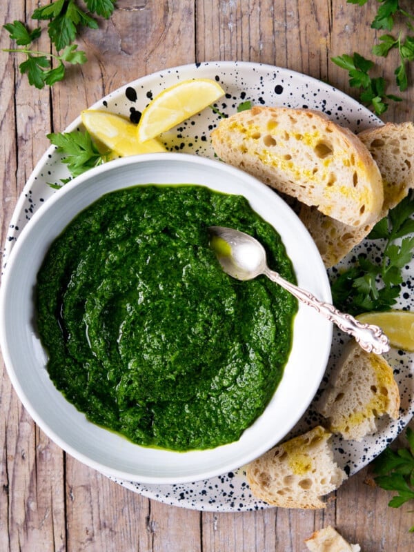Parsley pesto in a white bowl with a spoon