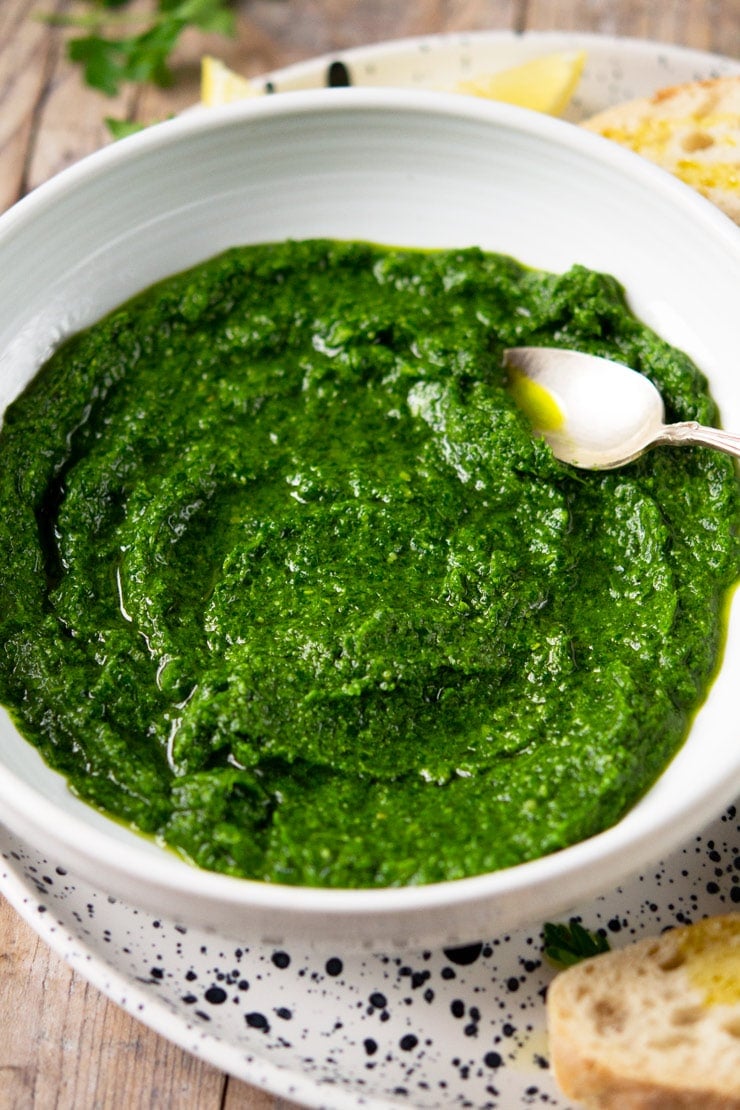A close up of parsley pesto in a white bowl 