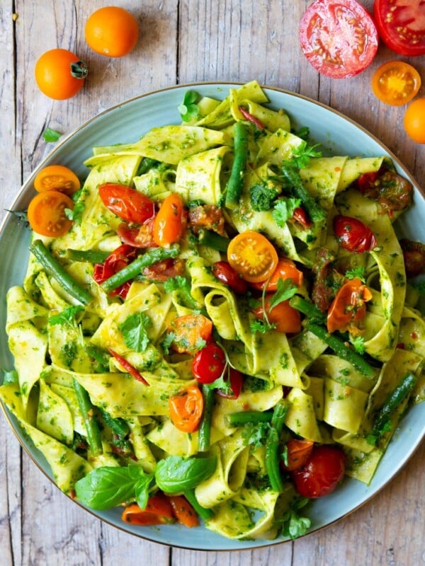 An overhead shot of pasta with green beans, tomatoes and pesto