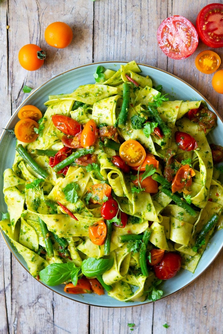 An overhead shot of pasta with green beans, tomatoes and pesto