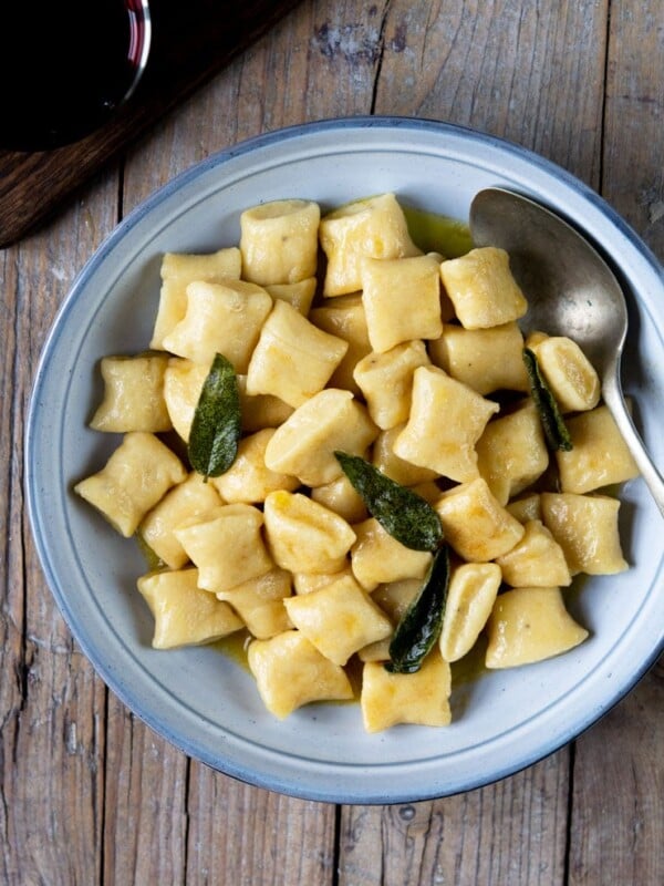 An overhead shot of gnocchi in a brown butter sage sauce in a large blue bowl