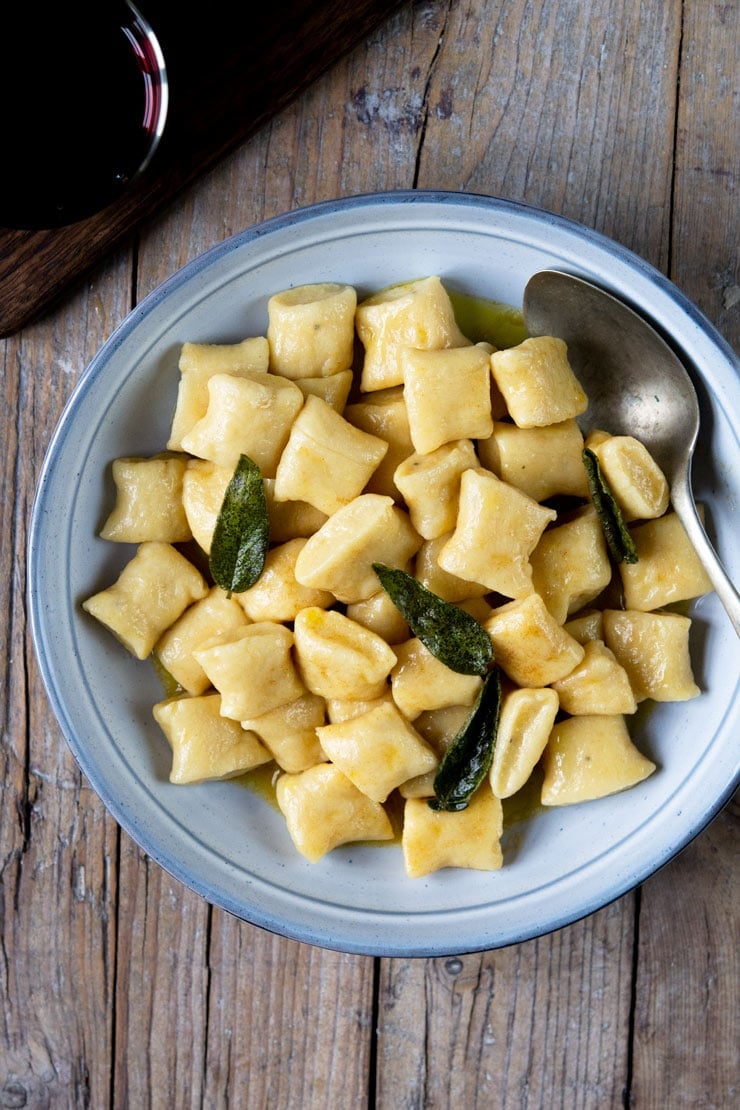 An overhead shot of gnocchi in a brown butter sage sauce in a large blue bowl