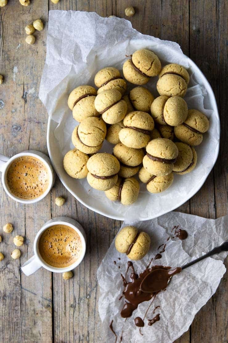 An overhead shot of lady's kisses cookies in a large bowl with coffees at the side