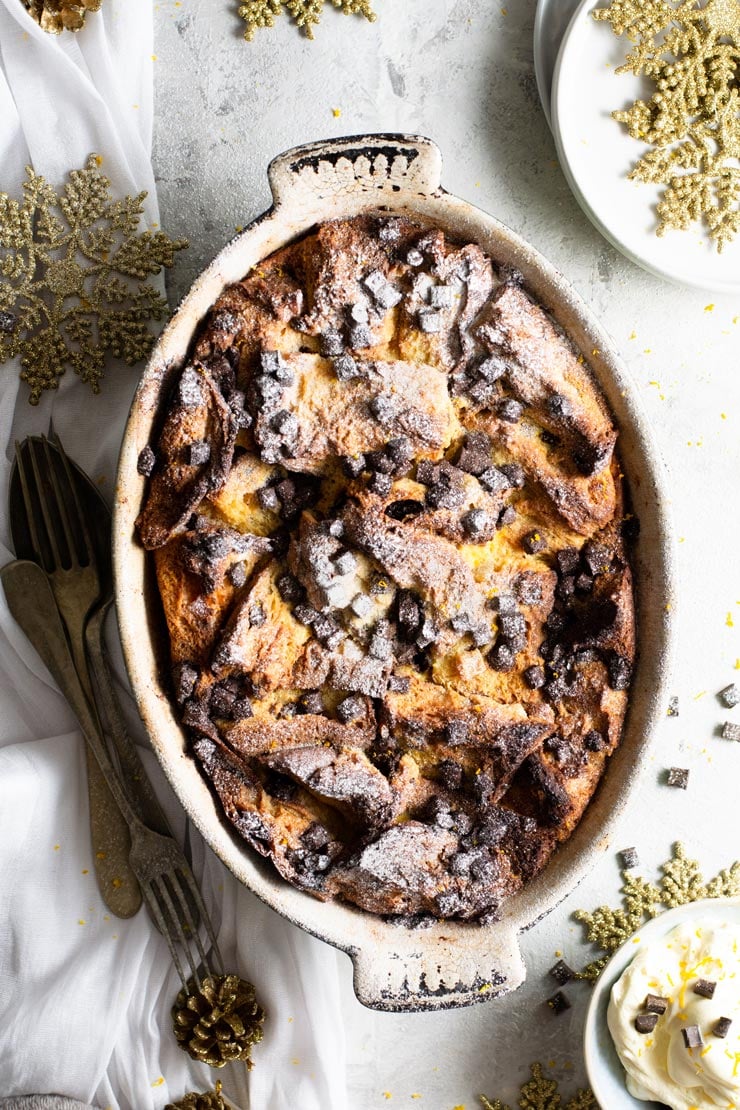 An overhead shot of panettone bread pudding in an oval baking dish with fresh cream at the side