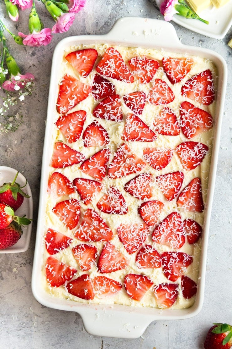 Light, creamy and delicious Strawberry Tiramisu made with juicy strawberries, Cointreau liqueur, and shavings of white chocolate. It's a fresh and summery spin on the classic Italian dessert that's just as delicious and easy to make. #tiramisu #strawberrydessert #Italiandessert An overhead shot of strawberry tiramisu in a rectangle dish