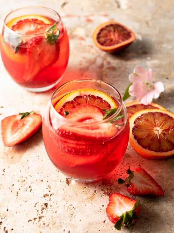 A campari cocktail in a round glass with strawberries