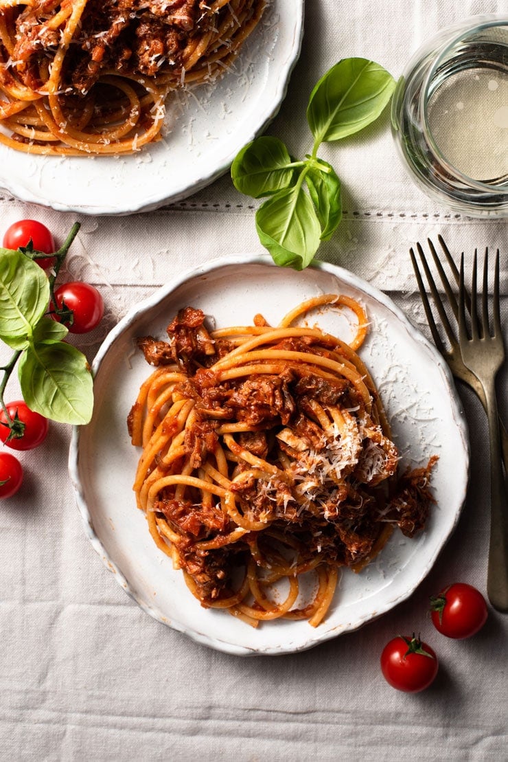 An overhead shot of leftover pulled pork ragu on a plate with wine and basil at the side