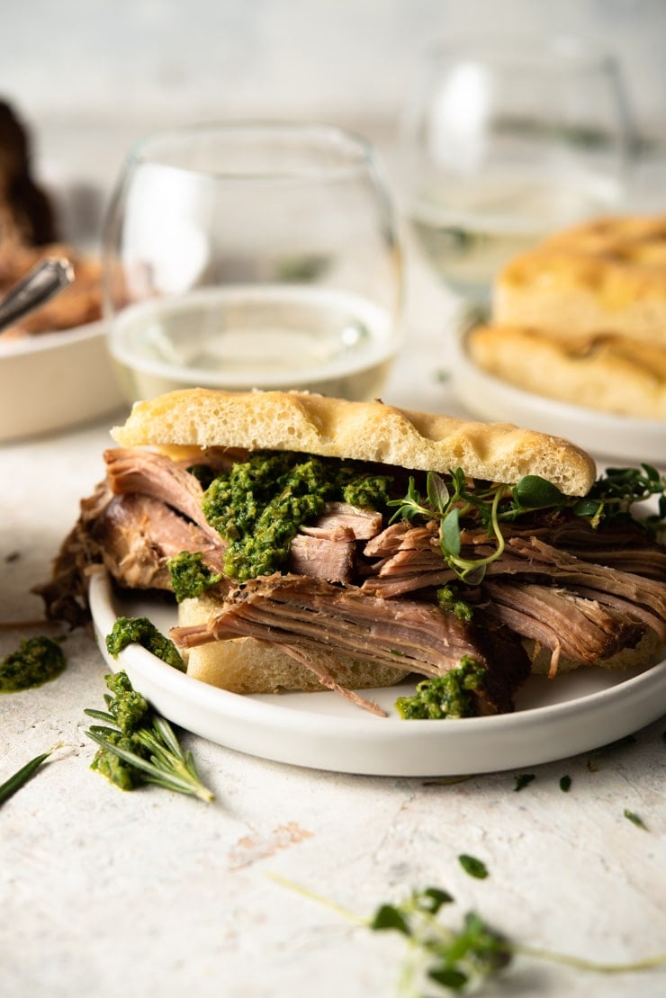 A close up of pulled pork with salsa verde on a sandwich