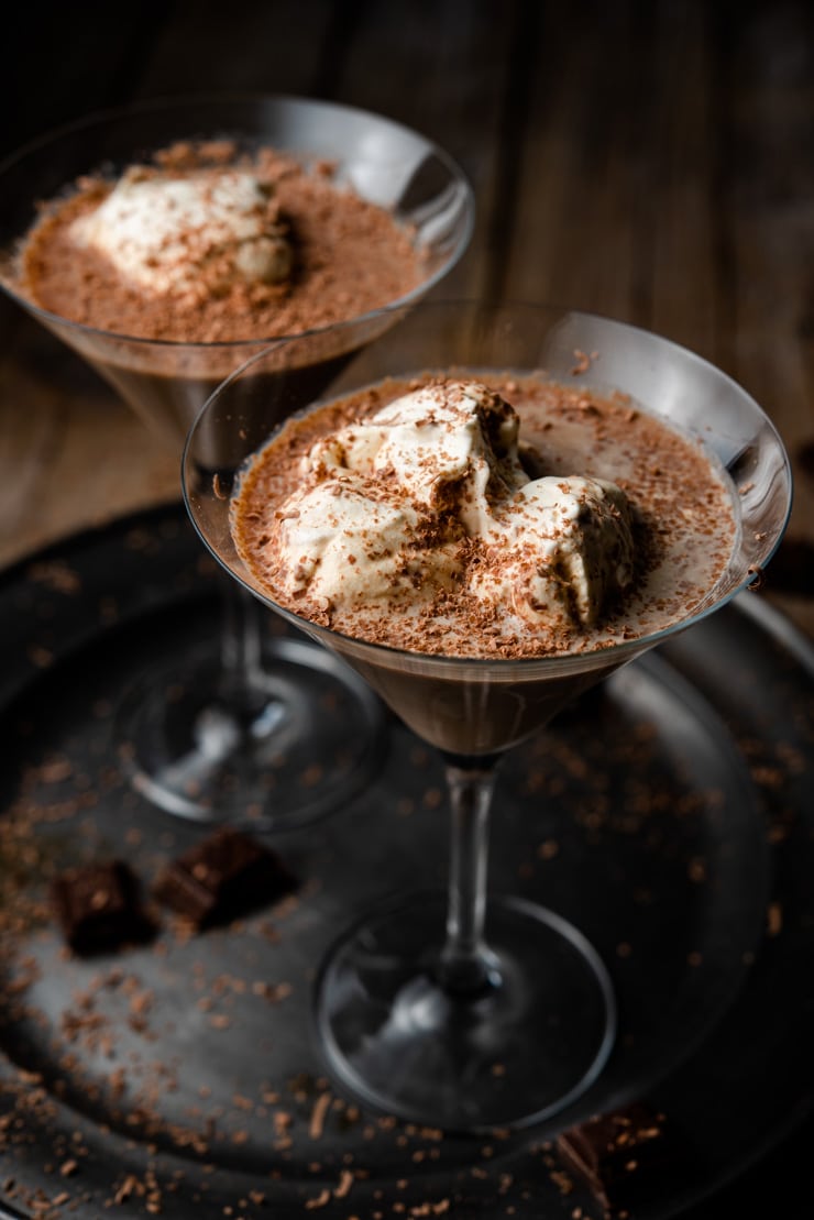 Two chocolate martinis on a pewter plate topped with whipped cream