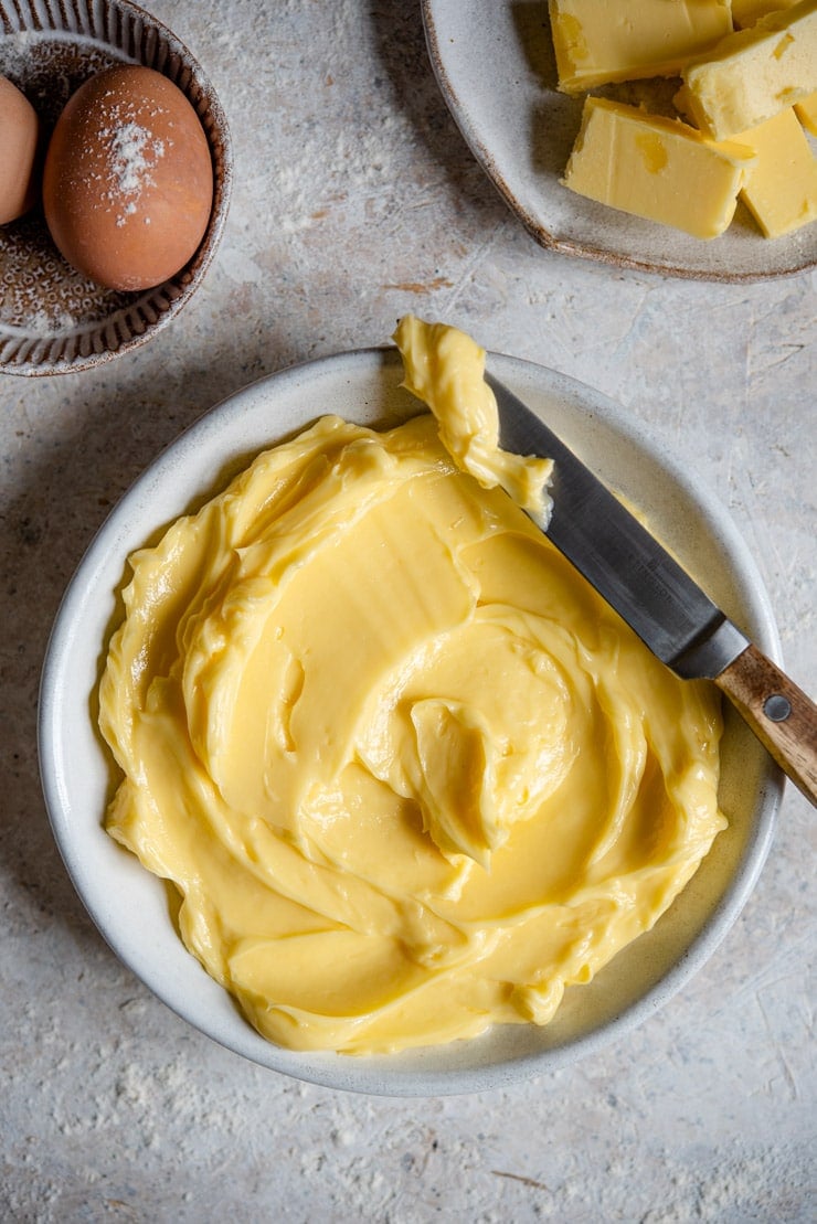 An overhead shot of softened butter in a rustic bowl