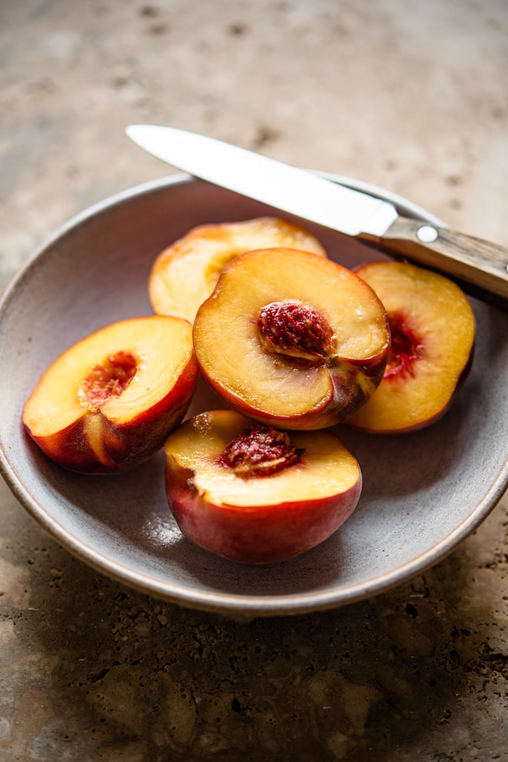 Fresh ripe peaches in a bowl with a knife at the side