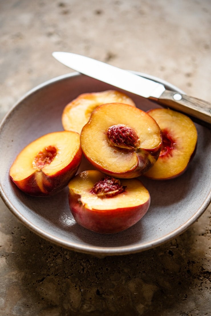 Fresh ripe peaches in a bowl with a knife at the side