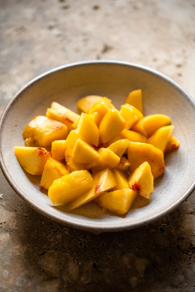 Chopped up fresh peaches in a bowl to make a peach bellini