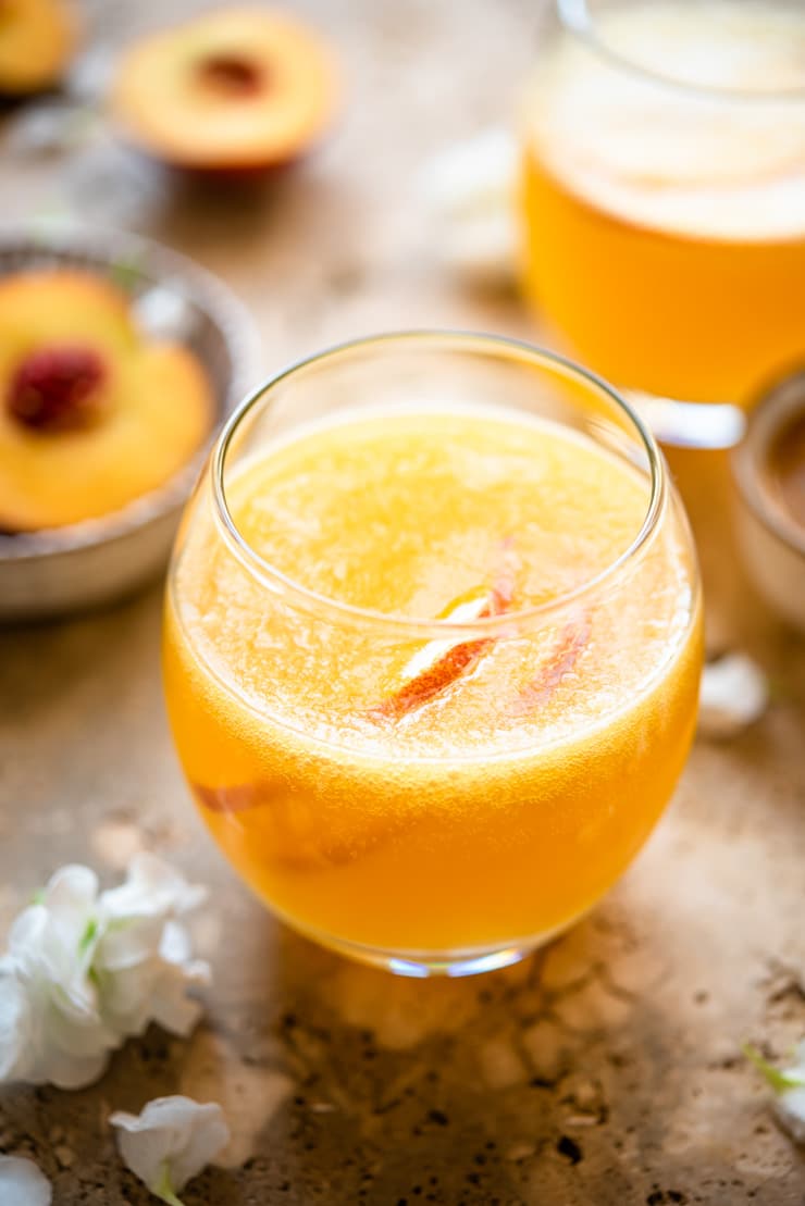 A close up of a peach bellini in a round glass