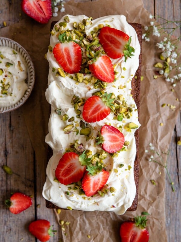 An overhead shot of a pistachio cake on a rustic wooden surface