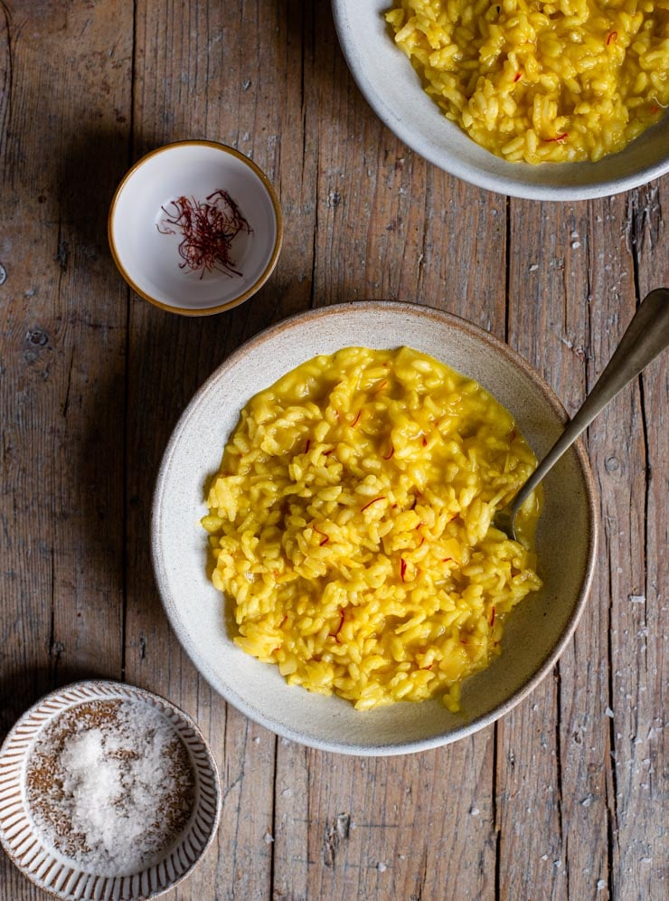 An overhead shot of a bowl of saffron risotto on a rustic wooden surface