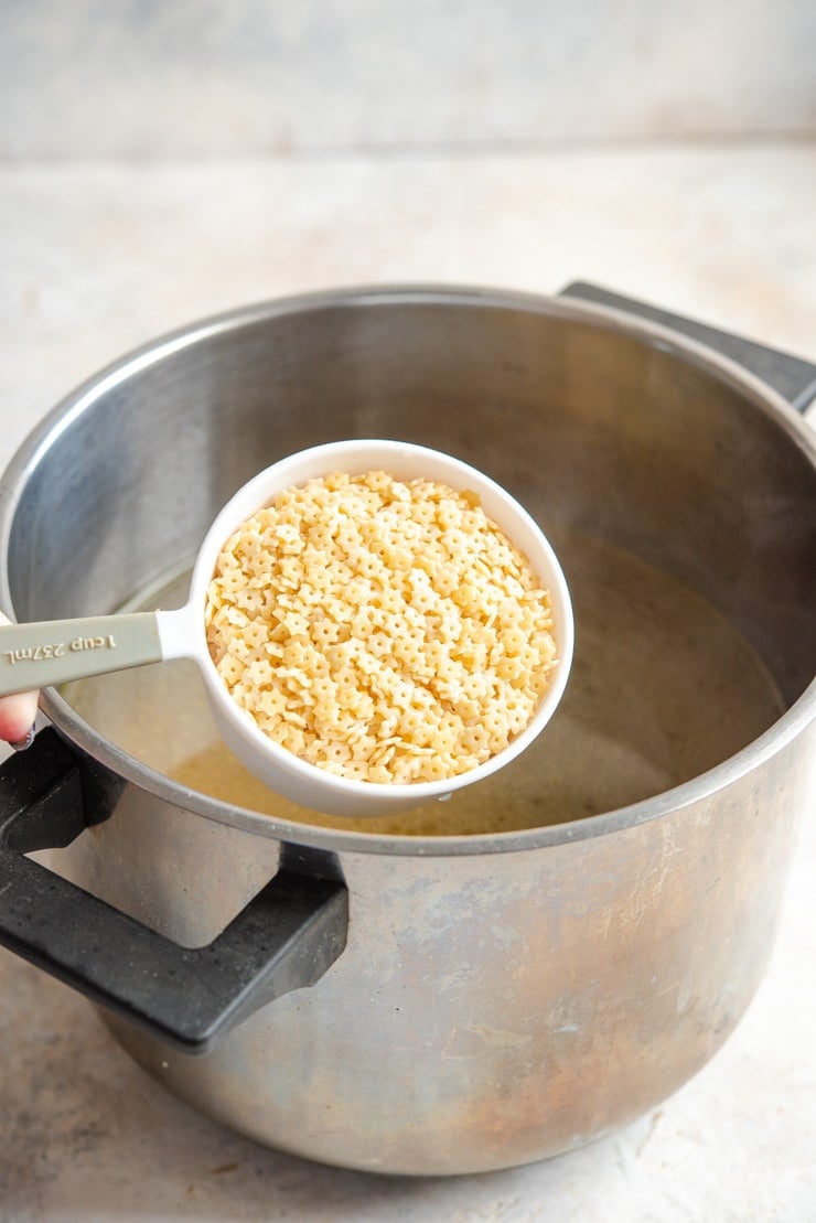 A photo of adding pastina pasta to chicken soup