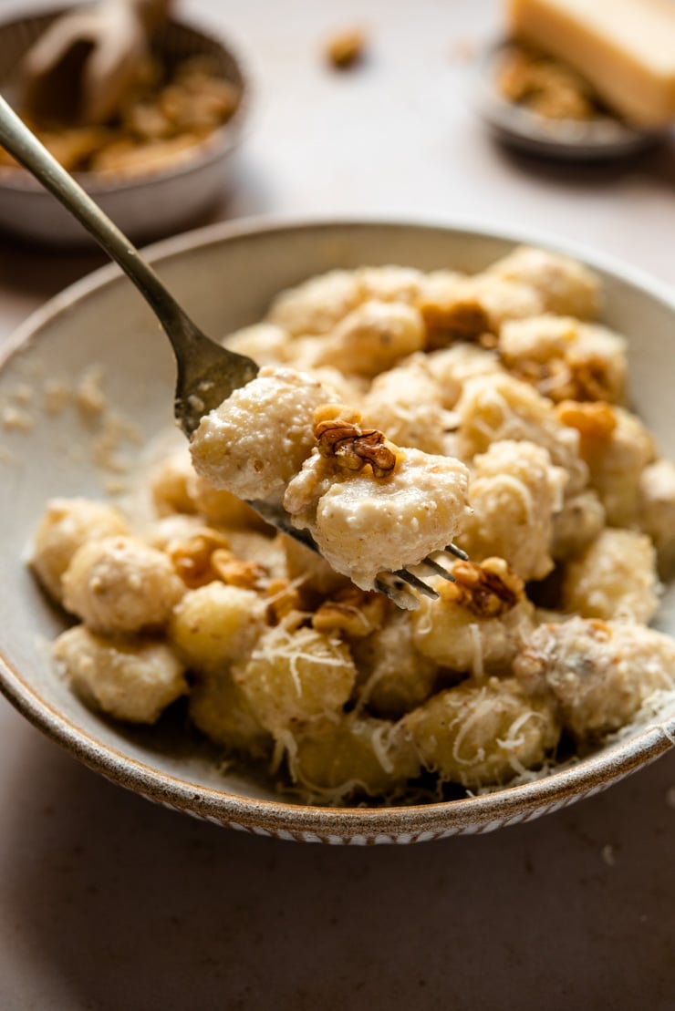 A close up of walnut sauce tossed with gnocchi on a fork