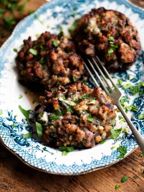 A white and blue patterned plate with 3 large mushrooms stuffed with sausage and gorgonzola.