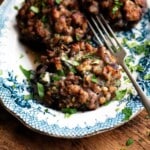 A close up of a portobello msuhroom stuffed with sausage and gorgonzola on a blue and white plate.