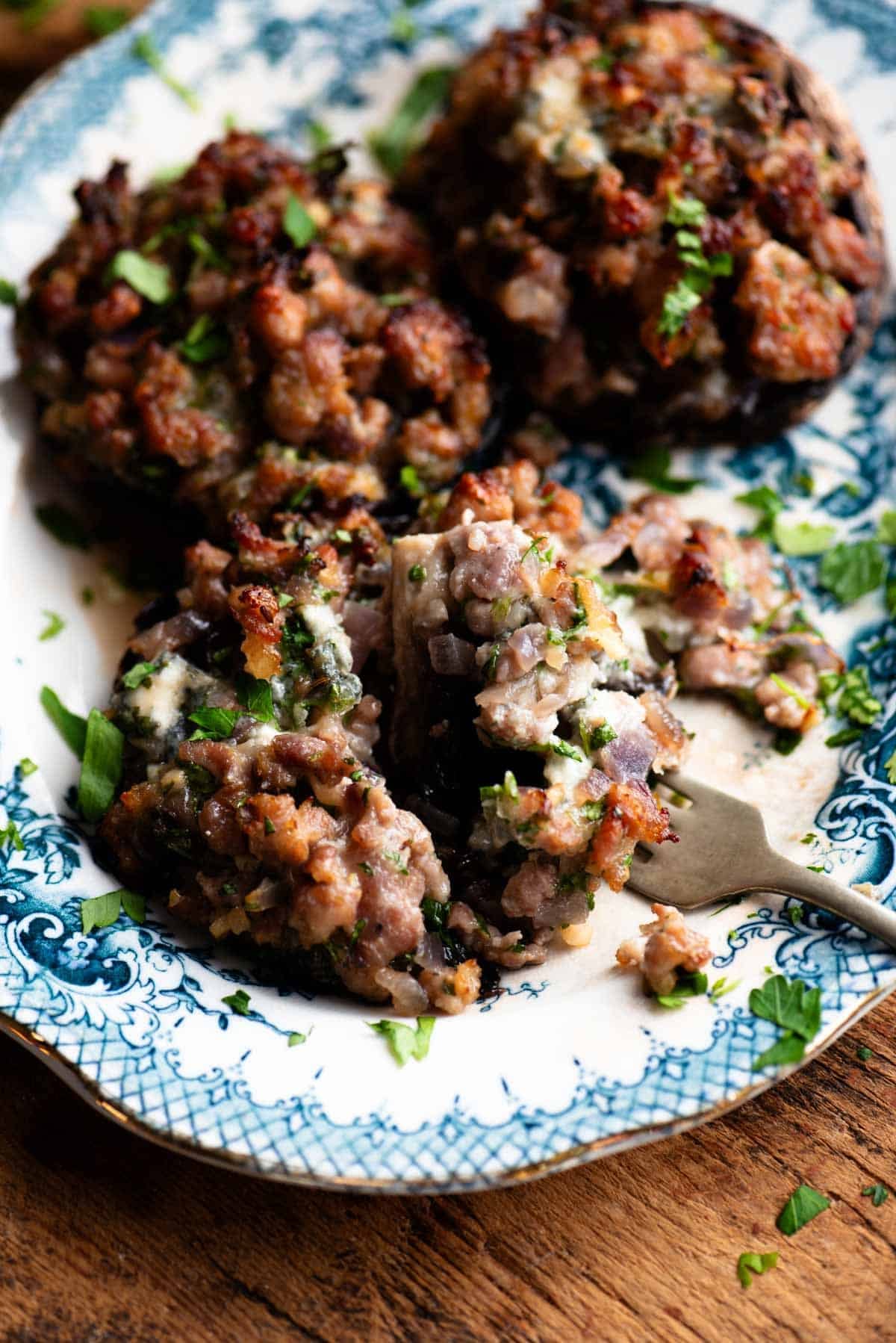 A close up of a stuffed mushroom cut open on a blue and white plate.