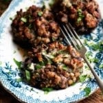Three sausage stuffed mushrooms on a blue and white plate.