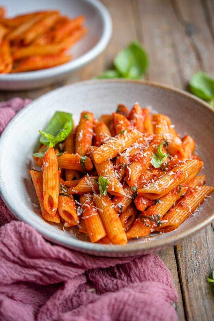 A side shot of penne pomodoro in a rustic bowl