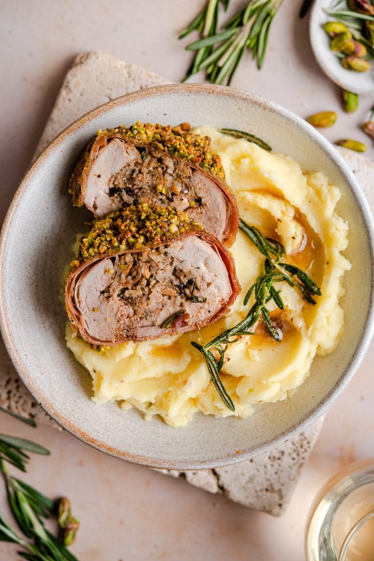 An overhead shot of stuffed pork tenderloin on top of mashed potatoes