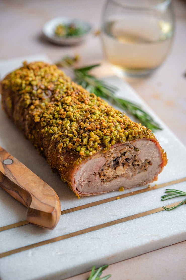 A whole stuffed pork tenderloin on a cutting board