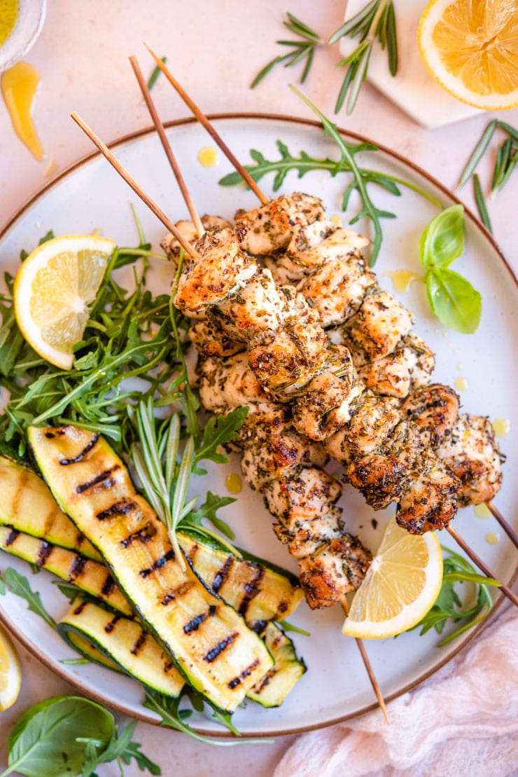 An overhead shot of chicken spiedini with grilled veg and arugula at the side