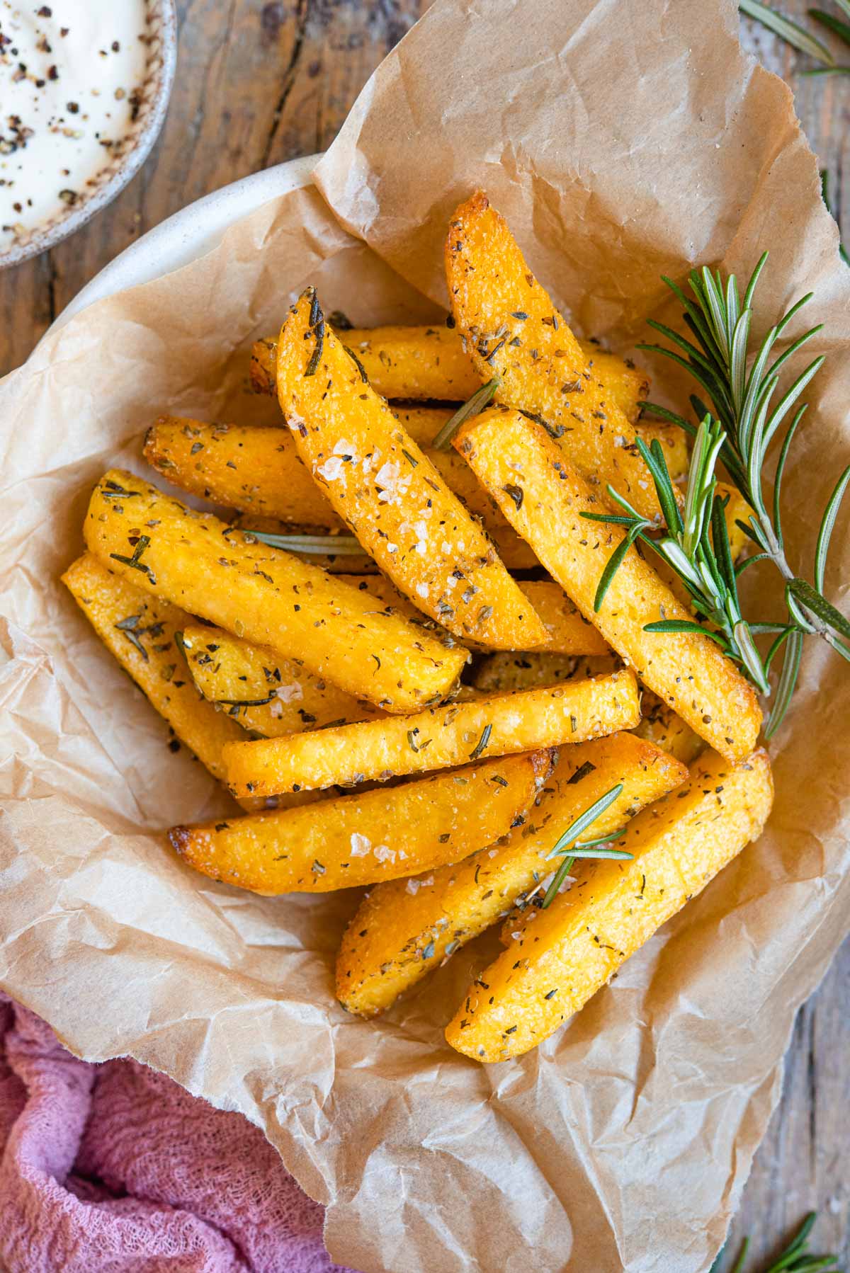 A close up of polenta cut into fries and served in a bowl with herbs