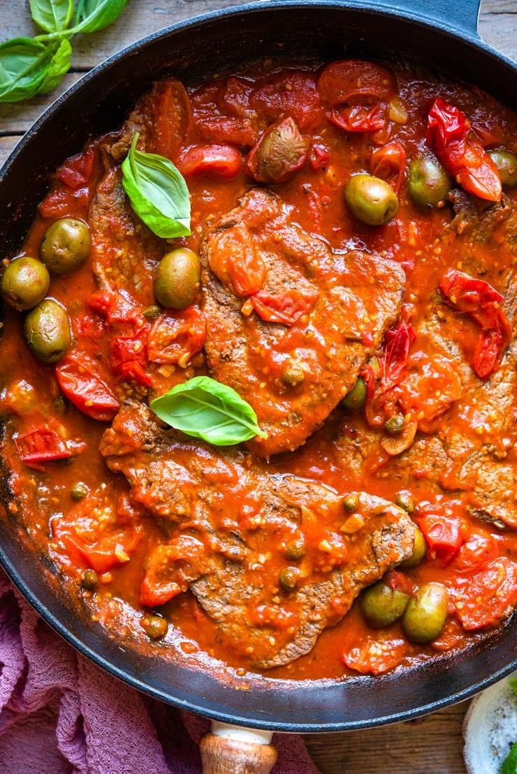 A close up of steak pizzaiola in skillet