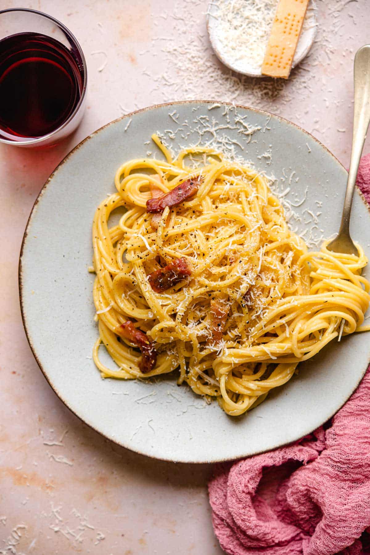 An overhead shot of spaghetti carbonara on a plate with a fork at the side with some spaghetti on it