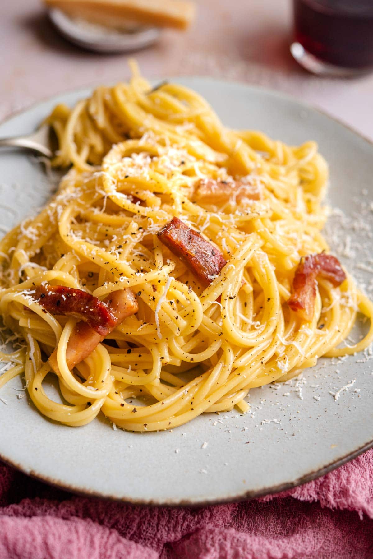 A side shot of spaghetti carbonara on a plate with a fork