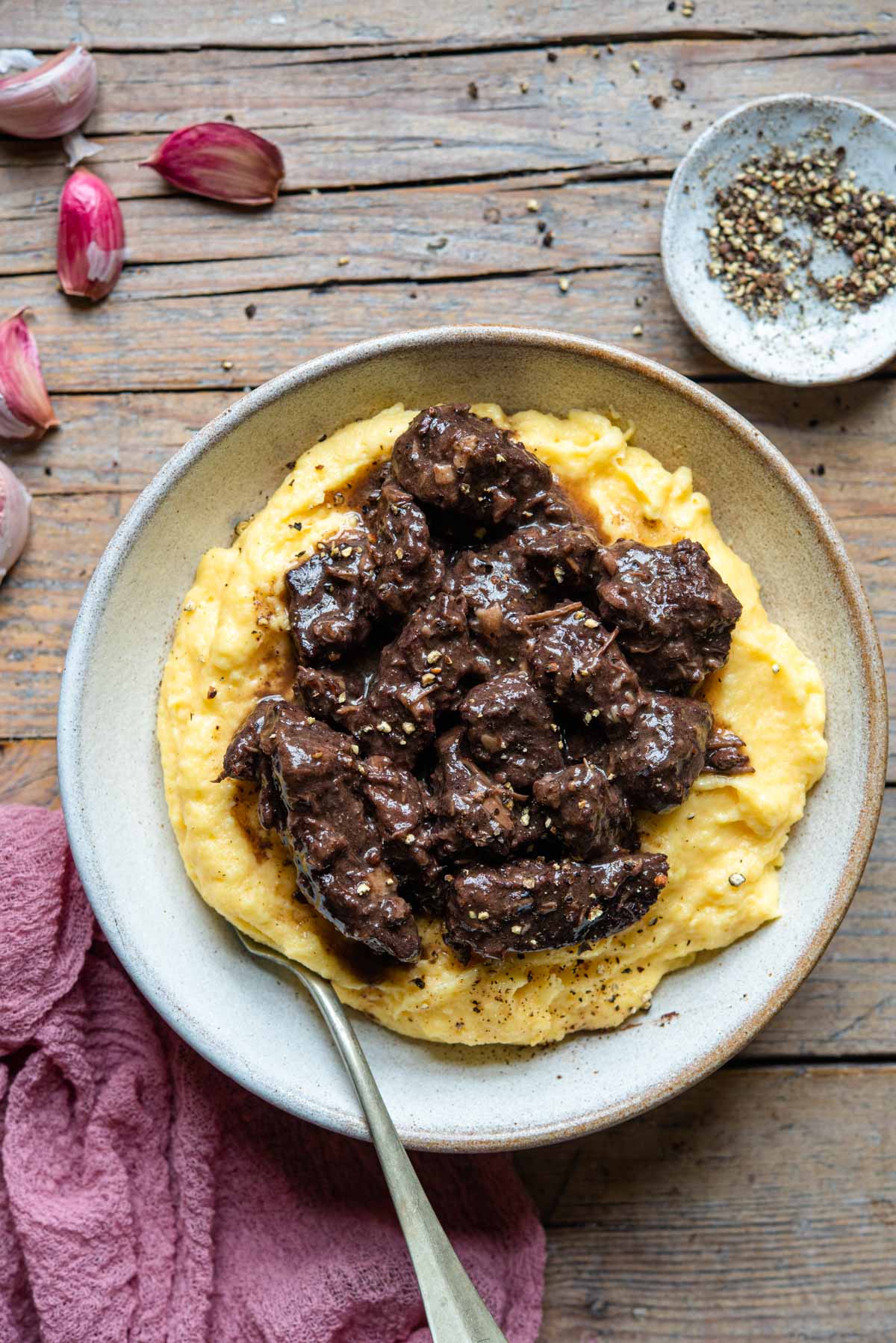 An overhead shot of Peposo, Tuscan red wine beef stew in a bowl with polenta