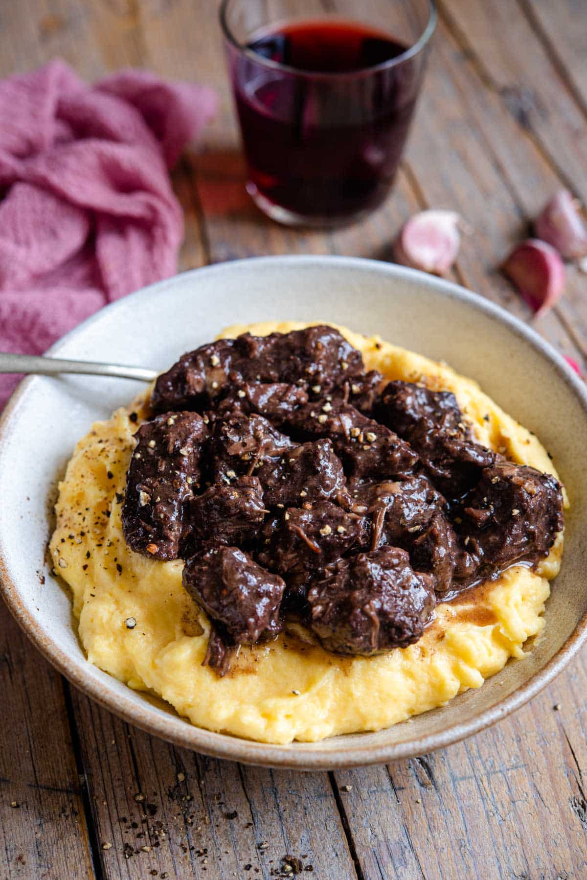 A side shot of polenta in a bowl stopped with beef stew