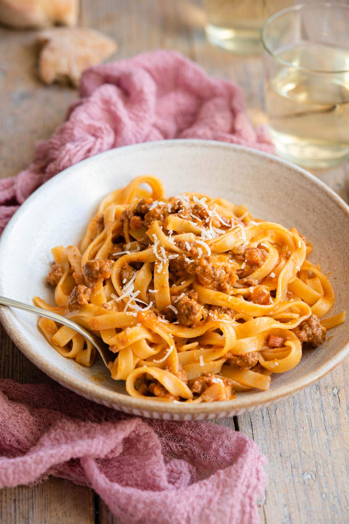 A side shot of bolognese sauce and tagliatelle in a rustic bowl