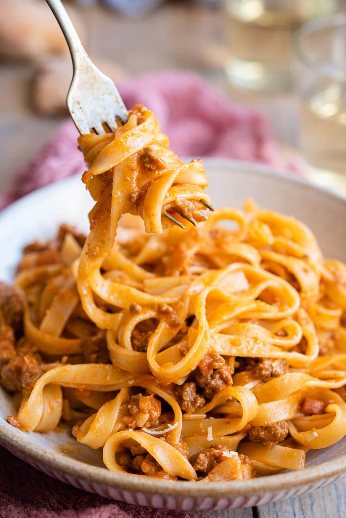 A close up of tagliatelli and bolognese sauce on a fork