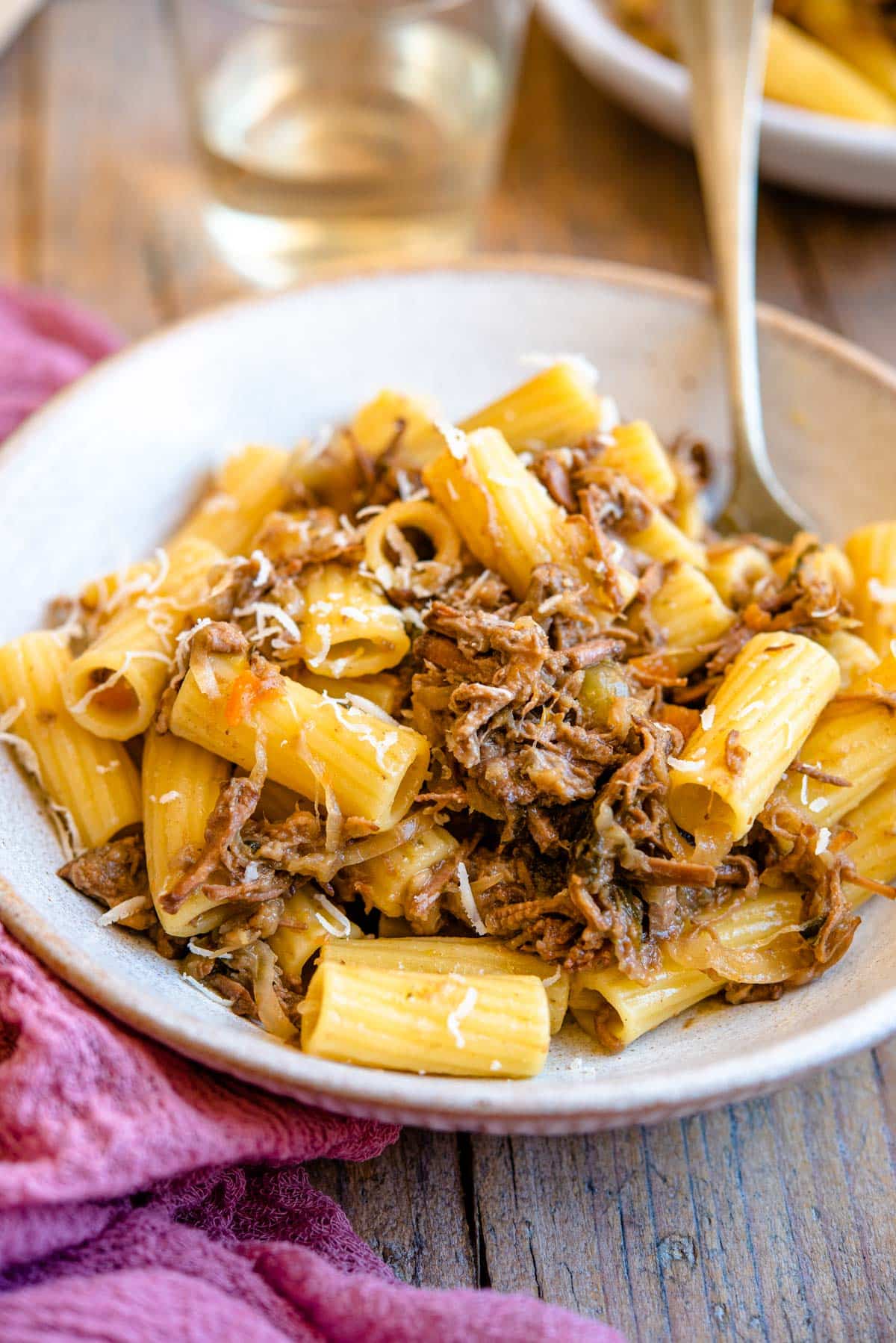 A side shot of a Neapolitan ragu tossed with rigatoni pasta in a rustic bowl